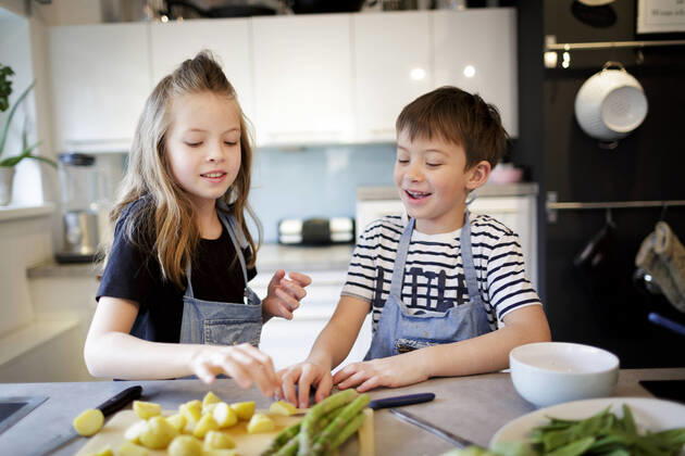 Portrait of girl and her little brother preparing vegetables in the kitchen model released Symbolfoto property released HMEF00869