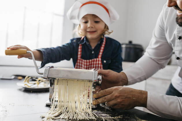 Father and daughter making homemade pasta with pasta machine in kitchen at home model released Symbolfoto property released JRFF04297