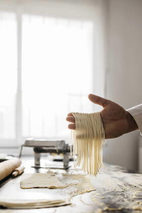 Hand holding homemade gluten free pasta in kitchen at home model released Symbolfoto property released JRFF04298