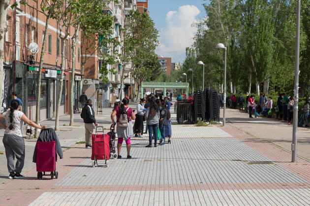 Spain: Food distribution due to Covid-19 crisis A large queue of people in the surroundings of the Aluche Neighbors Association wait while they guard the safety space between them to receive food. Madrid Madrid Spain Copyright: FerxCapdeponxArroyo