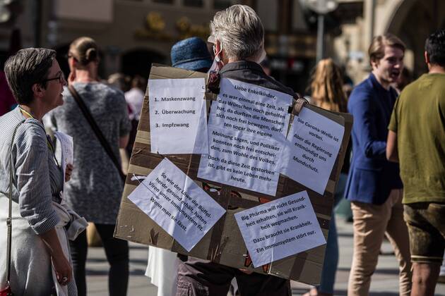 April 25, 2020, Munich, Bavaria, Germany: A man with various conspiracies written on his board during a QAnon-like demo in Munich, Germany. Organized in Telegram chats by conspiratorial â€oeQuerfront†(cross-front) groups, the city of Munich, Germany saw numerous anti-state â€oeCorona Parties†as under mottos such as â€oeDemonstration fuer die Erhaltung der Grundrechte†(Demonstration for the Upholding of Basic Rights) and â€oeFuer unsere Freiheit, unsere Grundrechte und unsere Selbstbestimmung†(Demonstration for our Freedom, Basic Rights, and Self-Determination). Numerous right-extremists, Verfassungsschutz-monitored figures, QAnon fans, and AfD politicians were in attendance. The groups are of the belief that the anti-Coronavirus measures are power-grabs. Querfront groups are often a mix of poli - ZUMAb160 20200425_zbp_b160_035 Copyright: xSachellexBabbarx