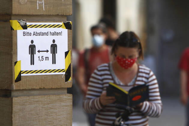Safety measures for keeping a distance in the city centre of Karlsruhe Poster with an inscription please keep a distance of 1.50 metres and a reading woman wearing a breathing mask at a bookstore, Baden Württemberg, Germany