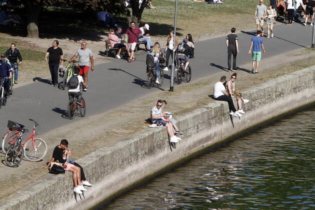 Passers-by enjoy the warm spring day and the sunshine during a walk on the riverbank promenade on the Main in Frankfurt, Hesse, Germany