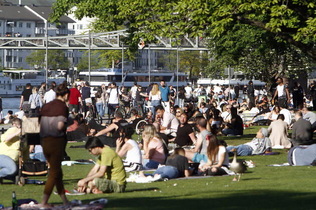 Despite the coronavirus crisis, curfews and contact bans, large numbers of sun-seekers enjoy the warm temperatures and sunshine on a sunbathing lawn on the banks of the Main in downtown Frankfurt and do not always keep the minimum distance.