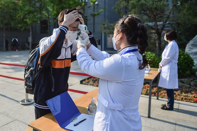 (200427) -- BEIJING, April 27, 2020 -- A staff member measures body temperature for a student at Beijing No. 161 High School in Beijing, capital of China, April 27, 2020. Senior high schools in Beijing on Monday restarted classes for seniors, who will take the national college entrance exam on July 7-10. ) CHINA-BEIJING-STUDENTS-BACK TO SCHOOL (CN) PengxZiyang 