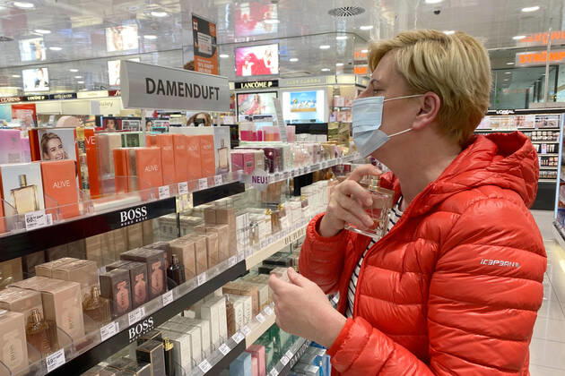 Relaxation and compulsory masks in the coronavirus pandemic Businesses in Bavaria will open again on April 27th. A woman is testing a perfume, womens fragrance, shop, branch, entrance, in a drugstore despite mouth nose protection,