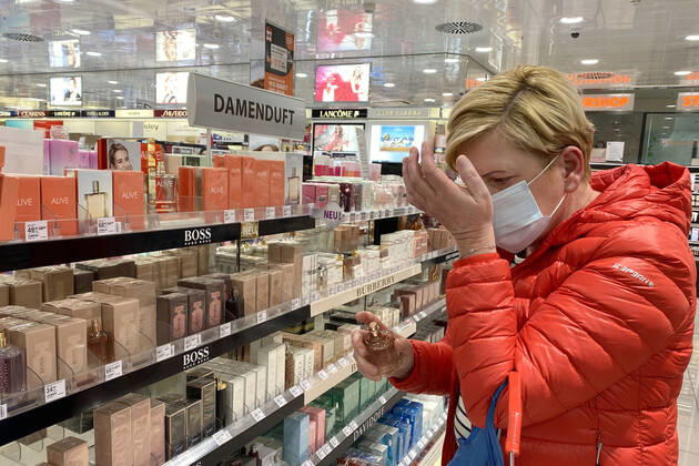 Relaxation and compulsory masks in the coronavirus pandemic Businesses in Bavaria will open again on April 27th. A woman is testing a perfume, womens fragrance, shop, branch, entrance, in a drugstore despite mouth nose protection,