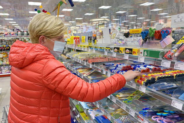 Relaxation and compulsory masks in the coronavirus pandemic Businesses in Bavaria will reopen on April 27th. A woman with a mouth nose protection in the stationery department of a drugstore store, branch, entrance,