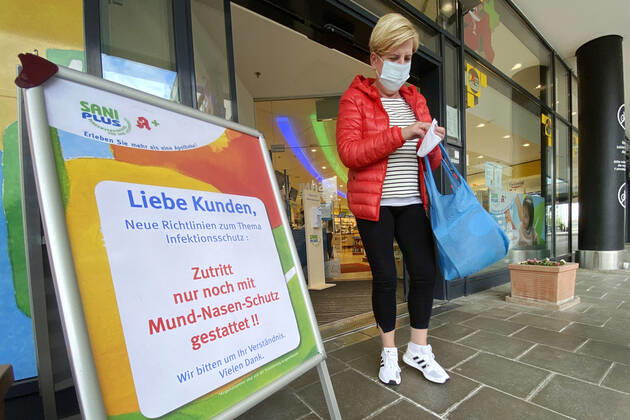 Relaxation and compulsory masks in the coronavirus pandemic Businesses in Bavaria will open again on April 27th A woman with mouth and nose protection will come from a SaniPlus pharmacy next to a notice, Operator access only allowed with mouth and nose protection ,
