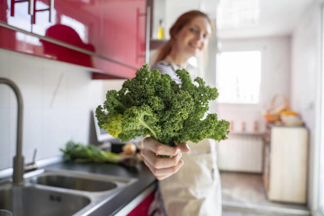 Young woman standing in kitchen, holding cale model released Symbolfoto property released AFVF06039