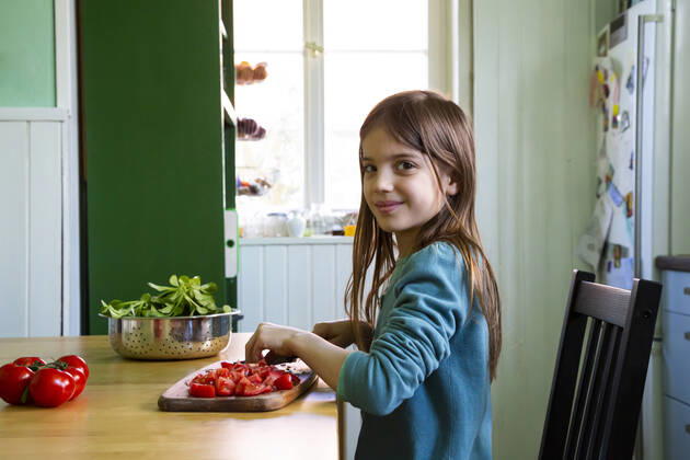 Smiling girl cutting tomatoes on chopping board in kitchen model released Symbolfoto property released LVF08809