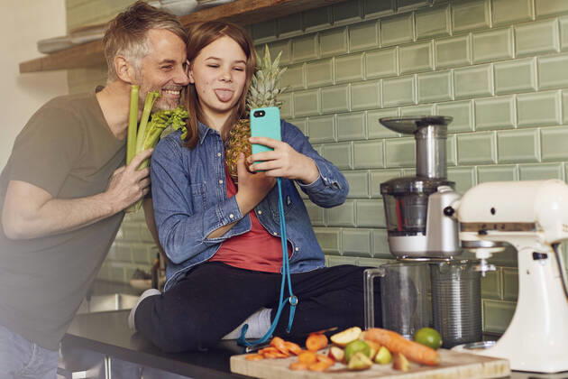 Happy father and daughter in kitchen making a selfie with fruit and vegetable model released Symbolfoto property released MCF00718