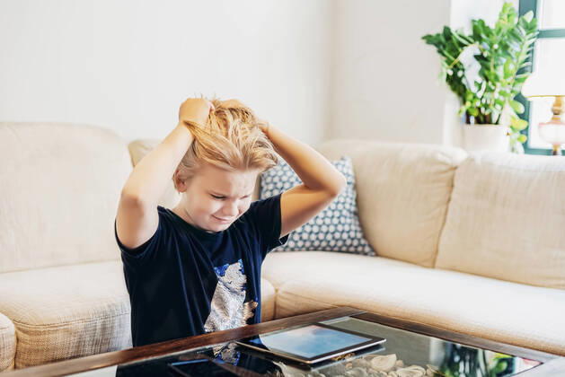 Frustrated boy with smartphone and tablet in living room model released Symbolfoto property released MJF02459