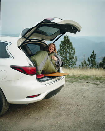 Woman in sleeping bag laughing while car camping in Big Sur Big Sur, CA, United States CR_ISKO200402B-262876-01,model released, Symbolfoto
