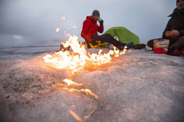 Campfire moves across the glacier as two men camp on a glacier. Pangnirtung, NU, Canada CR_JDIP200518-319539-01,model released, Symbolfoto