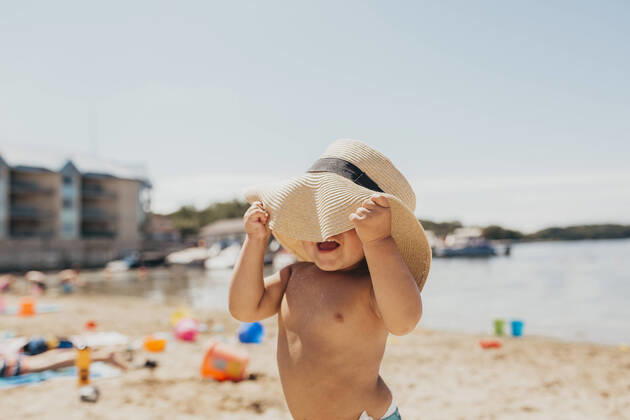 IMAGO Creative, Jahreszeit Sommer, Sonnenschutz Toddler Boy Playing Peek-a-boo with Sun Hat on Beach Milwaukee, WI, United States CR_SUWE200424C-371586-01,model released, Symbolfoto