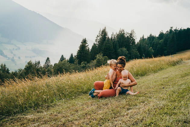 IMAGO Creative, Jahreszeit Sommer, Sommerferien Mom and kids hugging in the mountains sitting on ground Maria Alm, Salzburg, Austria CR_TANI200518-373645-01,model released, Symbolfoto