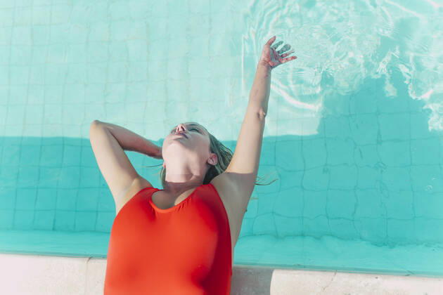 Woman wearing red swimsuit lying at the poolside model released Symbolfoto property released ERRF03663