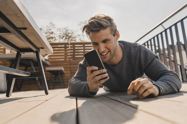Young man using smartphone on the bacony model released Symbolfoto property released KNSF08051