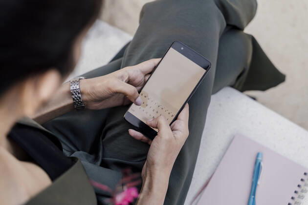 Close-up of female professional using smart phone while sitting on seat model released Symbolfoto AFVF06758