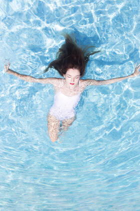 Young woman with eyed closed relaxing on swimming pool at resort during sunny day model released Symbolfoto JPTF00553