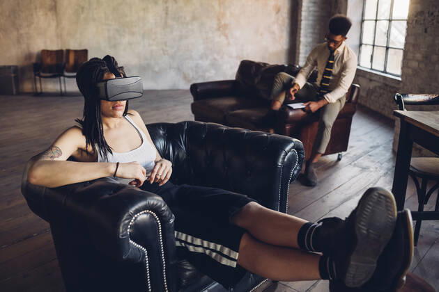 Young woman relaxing in armchair in loft office wearing Vr goggles model released Symbolfoto property released MEUF00739