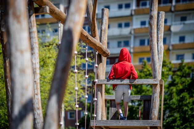 31 July 2020 Leipzig Saxony , Gruenau district A child is standing on a playground in front of a prefabricated building in Leipzig Gruenau