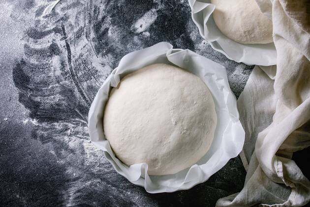 Process of making homemade bread. Fresh dough redy for baking on baked paper over black table with flour. Home bread baking. Photo series. Flat lay, space ÂNatashaBreen REDA&CO 1028_29_NBR8111