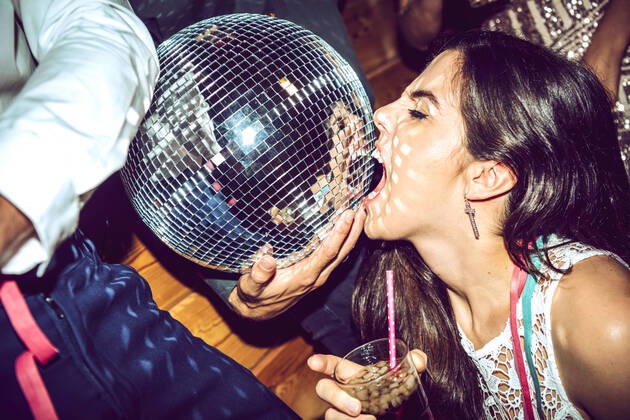 Young woman with eyes closed holding drink and biting disco ball in glamorous party model released Symbolfoto property released EHF00666