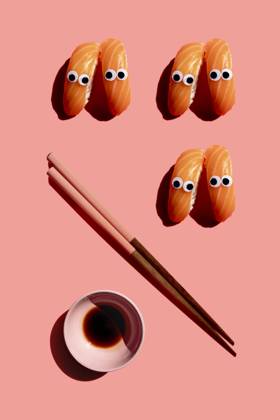 Studio shot of chopsticks, bowl of soy sauce and salmon nigirizushi pieces with googly eyes GEMF03928