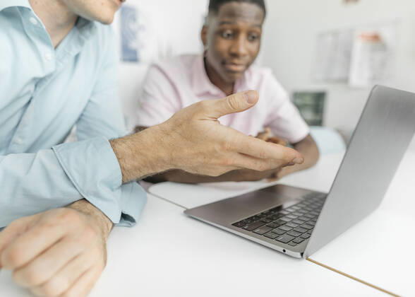 Colleagues working on laptop over table while sitting in office model released Symbolfoto property released KMKF01461