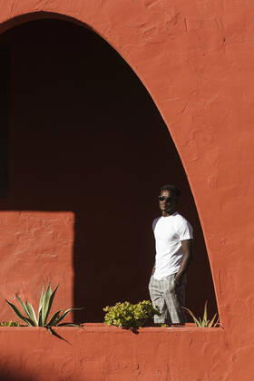 Young man wearing sunglasses standing by red wall during sunny day model released Symbolfoto property released LJF01686