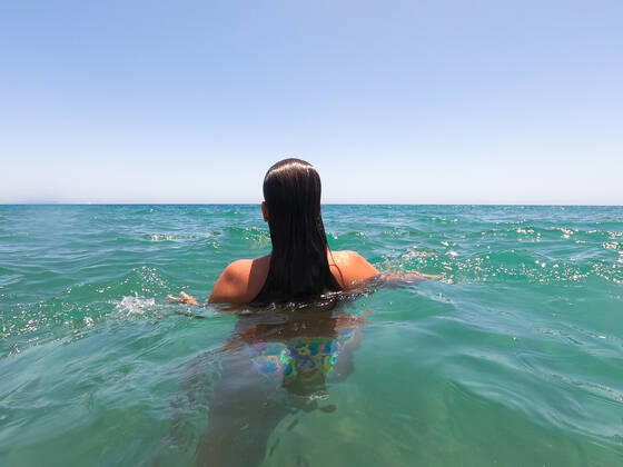 IMAGO Creative, Jahreszeit Sommer, Sommerferien Rear view of a young woman alone in transparent water on the beach Pasito Blanco, CN, Spain CR_GUMU200901B-489014-01 ,model released, Symbolfoto