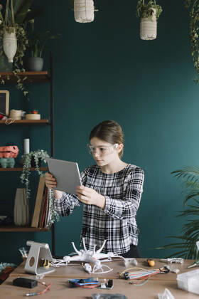 Girl using digital tablet while making quadcopter on table at home model released Symbolfoto property released ALBF01525