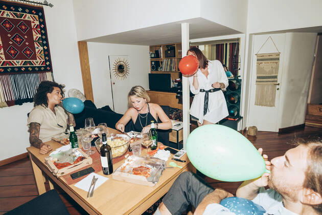 Male and female friends blowing balloons during party at home model released Symbolfoto property released MEUF01994