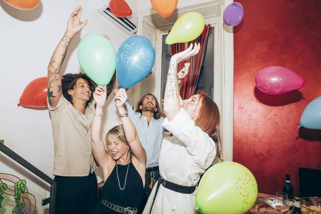 IMAGO Creative: Guten Rutsch Happy carefree friends dancing with balloons during party at home model released Symbolfoto property released MEUF01999
