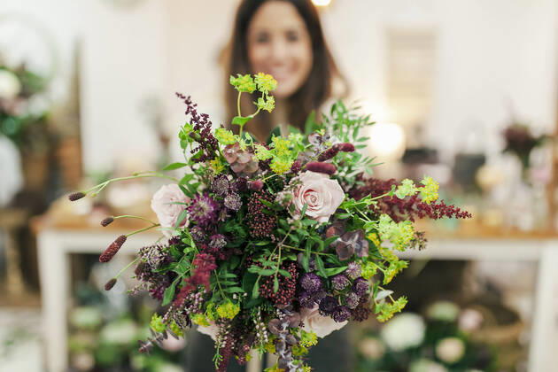 Woman holding bunch of flowers while standing at flower shop model released Symbolfoto property released MRRF00402