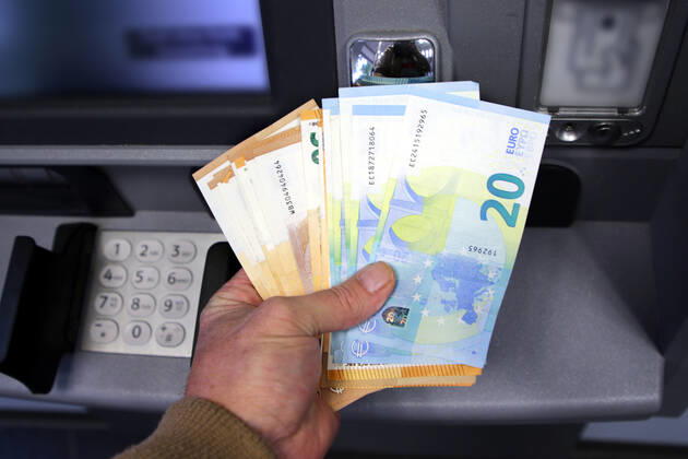Cash supply from an ATM A person fetches a large amount of cash in 50 and 20 euro banknotes from an ATM