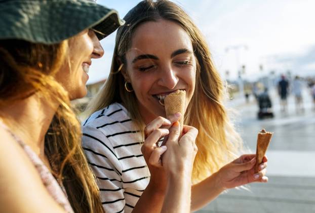 Smiling young woman feeding ice cream to sister while spending enjoying in city model released Symbolfoto MGOF04493