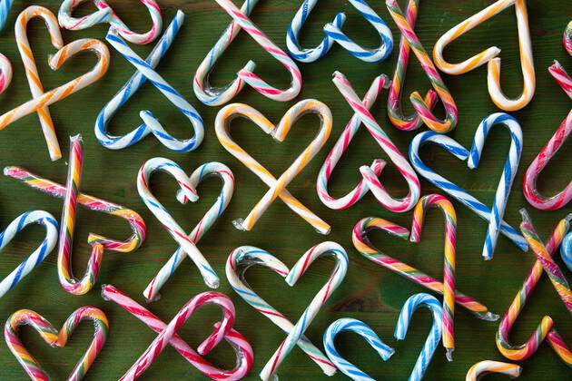 Colorful candy canes in hearts arranged on a green background 1079706386