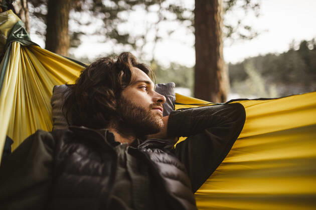 IMAGO Creative: Klimawandel - Nachhaltiges Reisen Contemplating man looking away while lying over hammock in forest, MA82659, Sweden, Stockholm, model released