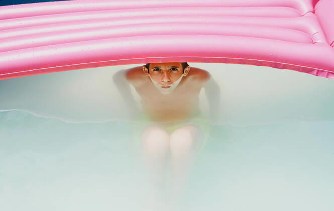 IMAGO Creative: 2021 Favoriten IMAGO Creative: Kraft des Wassers Boy in a pool taking a bath under a pink flat looking at camera. Zaragoza, Aragon, Spain CR_RUBO201207B-575453-01 ,model released, Symbolfoto