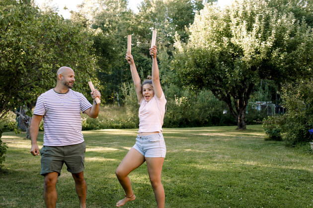 Father looking at daughter with hand raised while playing molkky in yard, MA82696, Sweden, Stockholm Archipelago, model released Copyright: xMaskotx