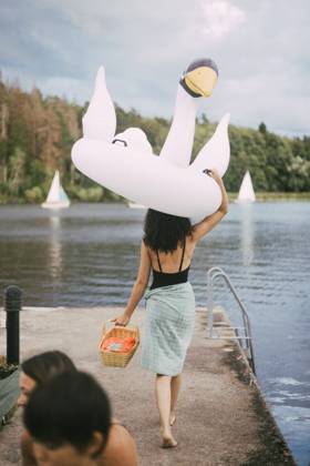 IMAGO Creative, Jahreszeit Sommer, Sommerferien Rear view of teenager carrying inflatable ring overhead while walking towards lake, MA83041, Sweden, Stockholm, model released Copyright: xMaskotx