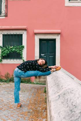 Young slim casual woman stretching on street of old city while dancing gracefully, Model released Copyright: xAlexandraxCoelhox MR