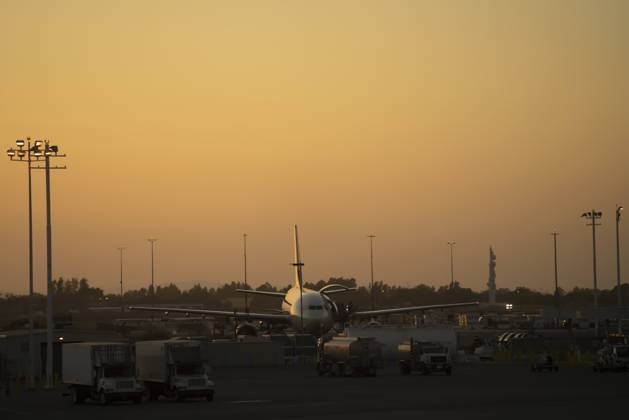 Distant shiny aircraft surrounded with service vehicles on airfield in sunset in USA, Model released Copyright: xJuanxMiguelxApariciox MR