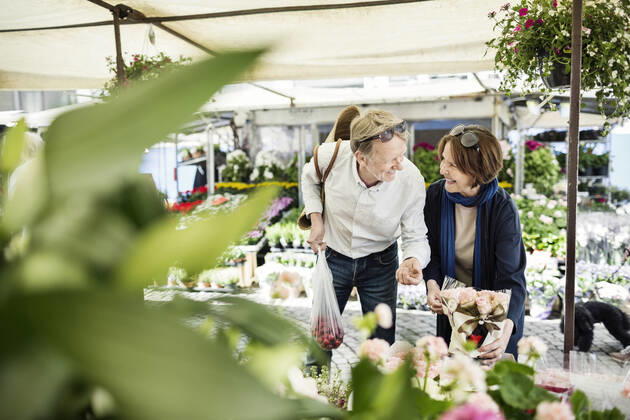 Happy senior couple talking while buying flowers at market , model released Copyright: xMaskotx , MA45749
