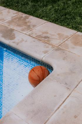 From above of basketball ball in corner on swimming pool in terrace of house with green grass Copyright: xEkaitzxGeriquex Model Released