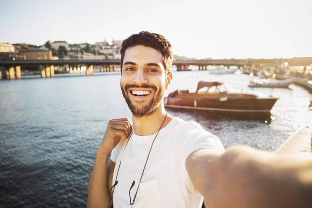 IMAGO Creative, Jahreszeit Sommer, Sommer in der Stadt Portrait of happy male tourist by river in city , model released Copyright: xMaskotx , MA47343