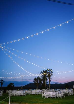 Glowing garlands hanging over banquet tables and chairs prepared for wedding party in evening Copyright: xGabrielxTrujillox Model Released
